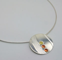 round silver pendant with copper and brass